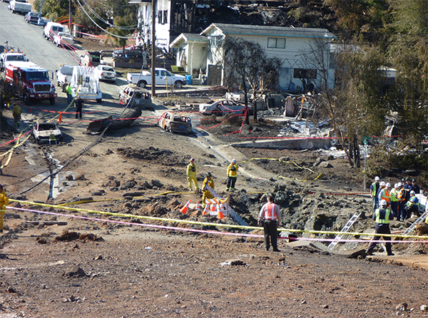 San Bruno, CA, accident scene with the crater in the foreground and the ruptured pipe section in the background